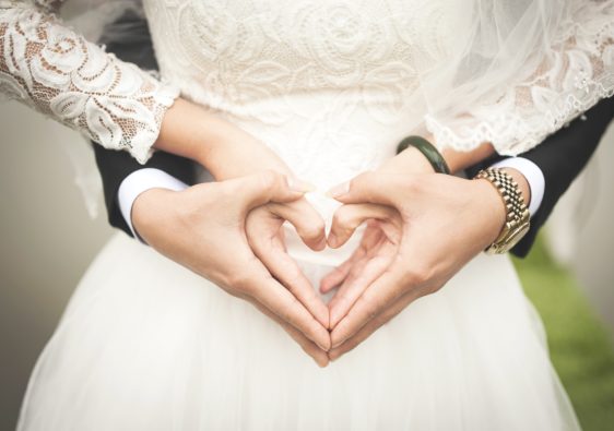 A wedding couple holding hands in the shape of a heart
